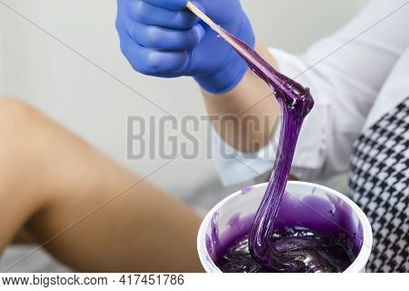 Closeup Of Female Beautician Hands Mixing Liquid Colorful Wax In Plastic Container For  Sugaring Pro
