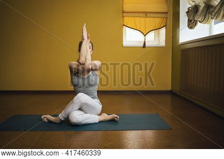 Woman In Gray Sportswear Practicing Yoga, Performing Gomukhasana Exercise, Cow Pose, Exercising Sitt