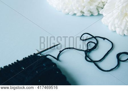 Unwound Thread. Knitting Black Yarn And A Ball Of Thread And Knitting Needles And White Flowers Peon