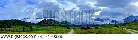Panorama Of Alpine Pasture With Wood And Mountain Range Background