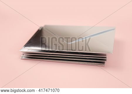 Stack Of Mirror Or Silver Paper Festive Envelope On Pink Isolated Background. Envelopes For Invitati