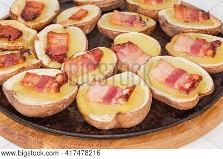 Potato Halves In Their Skins Baked With Bacon Slices On A Baking Sheet, Fragment Close-up In Selecti