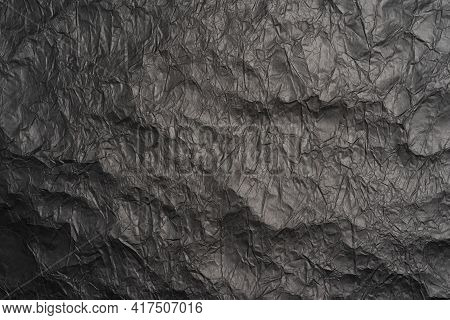Black Crumpled Paper Texture In Low Light Background. Black Matte Crumpled Paper Background, Abstrac