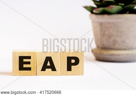 On A Light Background, Wooden Cubes With The Inscription Eap Employee Assistance Program And A Flowe