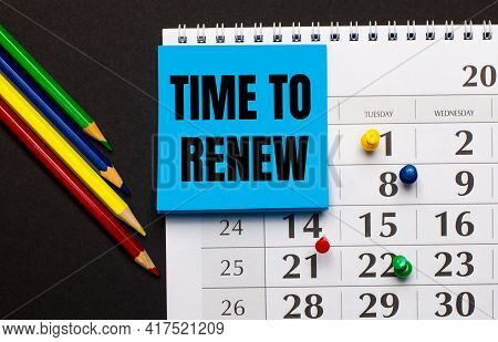 The Calendar Has Light Blue Note Paper With The Text Time To Renew. Nearby Colored Pencils On A Dark
