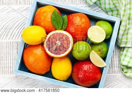 Various fresh citrus fruits in wooden box. Bood orange, lime, lemon. Top view flat lay