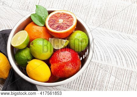 Various fresh citrus fruits in colander. Bood orange, lime, lemon. With copy space