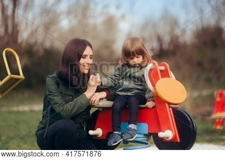 Child Having Fun On A Playground Supervised By Careful Mom