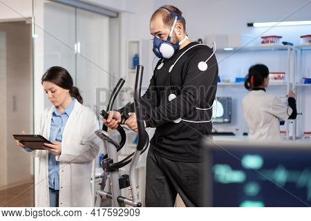 Performance Athlete Running On Cross Trainer With Electrodes Attached On Body