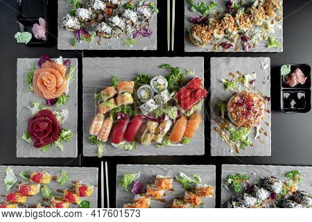 Top View Of Variety Of Japanese Dishes On Dark Background. Sushi With Tuna, Salmon, Agacate, Sashuim