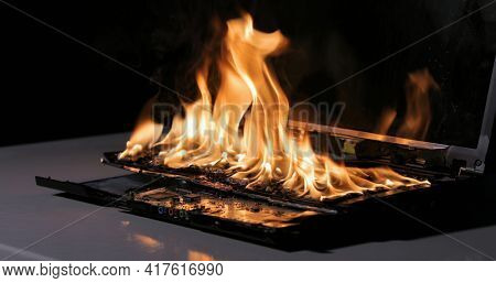 Laptop burning in flames on a desk, fire hazard. losing valuable data, closeup