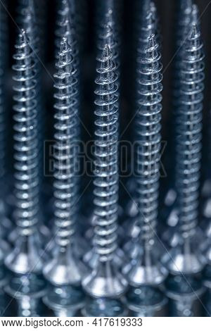 Standing Galvanized Self-tapping Screws On A Mirror Surface. Screws Macro Photo. Construction Abstra