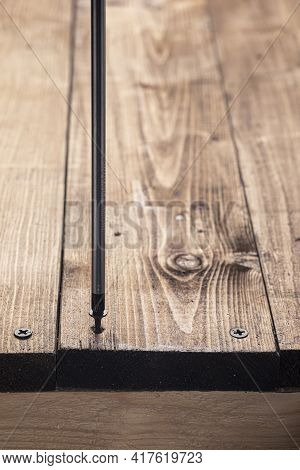 A Screwdriver And Screw On A Wooden Background. Screwdriver Of Chromium Vanadium Steel. Construction