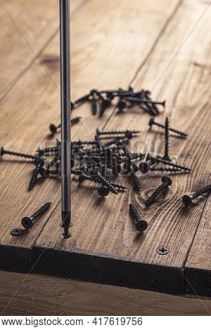 A Screwdriver And Screw On A Wooden Background. Screwdriver Of Chromium Vanadium Steel. Construction
