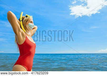 Funny Girl In Medical And Snorkeling Masks On Sea Beach. New Rules To Wear Face Masks At Public Plac