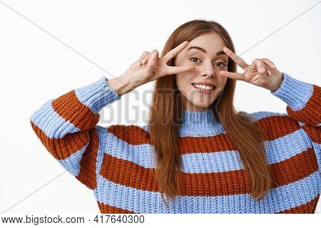 Happy Attractive Girl Showing Peace V-signs Over Eyes, Smiling With Wite Perfect Teeth, Standing Rel