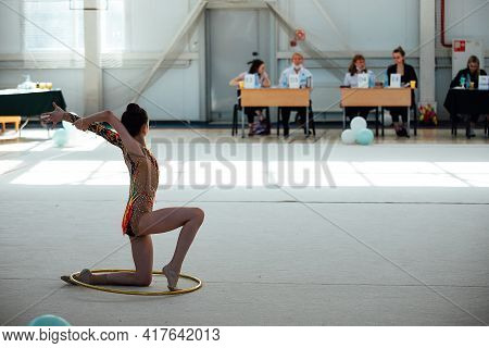 A Young Gymnast Deftly Jumps On A Performance With A Hoop In Front Of The Judges. Competition In The