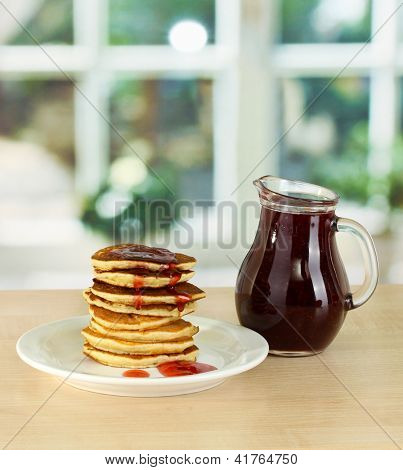 หวาน pancakes บนแผ่นกับแยมบนโต๊ะในห้องครัว