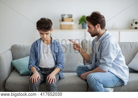 Family Discipline Concept. Grumpy Dad Scolding His Offended Son, Teaching His Kid Tolerance, Respect