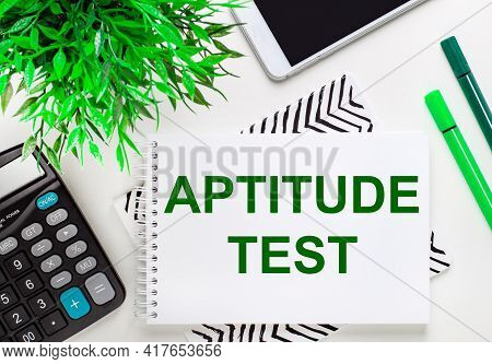 Calculator, Green Plant, Telephone, Marker, Notebook With The Text Aptitude Test On The Desktop. Fla