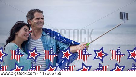 Composition of american flag stars over happy couple taking selfie with smartphone on selfie stick. american patriotism, culture and tradition concept digitally generated image.