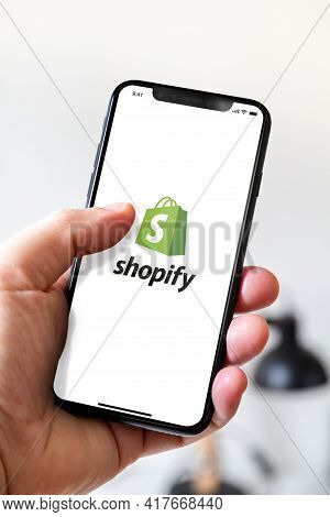 Paris - France - March 23, 2021 : Hand Holding Iphone Smartphone With Shopify Logo