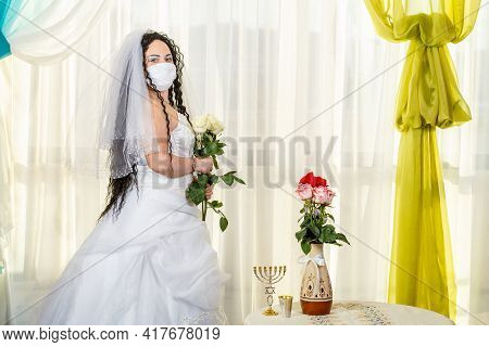 A Jewish Bride In A Synagogue At A Table With Flowers Before A Chuppa Ceremony During A Pandemic, We