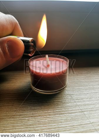 Lighting Candle With A Lighter. Hand Holding Lighter With Flame.
