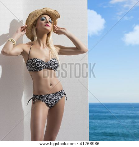 blonde MÃ¤dchen im Bikini in der NÃ¤he der Wand mit Hut