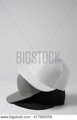 Closeup Shot Of Three Blank Monochrome White, Gray And Black Baseball Cap Isolated Over Light Backgr