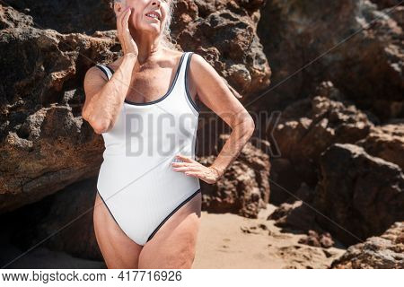 Senior woman in white one-piece swimsuit summer shoot