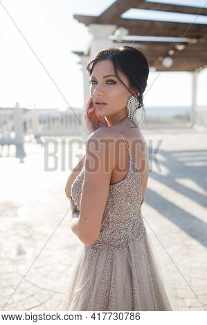 A Slender Brunette Girl In A Long Beautiful Evening Dress Spends Time Alone Outdoors On A Sunny Summ