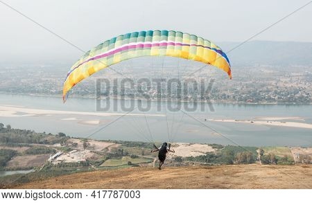 Paragliding In The Sky. Paraglider  Flying Over Landscape From Beautiful View Mekong River At Wat Ph