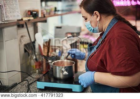 Concetrated Female Chef Cooking Something On The Stove