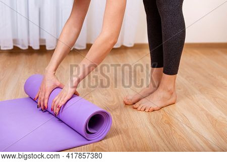 Close Up Of A Womans Hands Is Rolling Up Exercise Mat And Preparing To Doing Yoga. Equipment For Fit