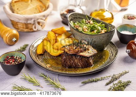 Steak With Grilled Duck Liver Served With Potato Wedges And Aragula On The Restaurant Table