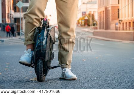 The Legs Of A Young Woman Ready To Ride An Electric Unicycle, Abbreviated Euc, Against The Backgroun