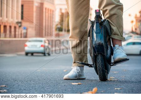 The Legs Of A Young Woman Ready To Ride An Electric Unicycle, Abbreviated Euc, Against The Backgroun