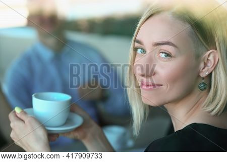Portrait Of Smiling Woman With Cup At Meeting In Cafe