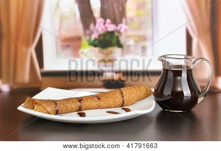 หวาน pancakes บนแผ่นกับนมข้นบนโต๊ะในห้อง