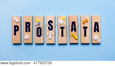 The Word Prostata Is Written On Wooden Blocks On A Light Blue Table Near The Pills. Medical Concept