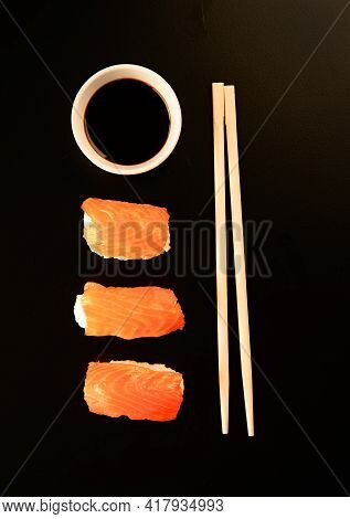 Set Of Sushi Rolls And Chopsticks, Isolated On Black Background