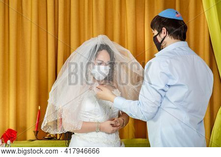 During The Chupa Ceremony In The Synagogue, The Masked Bride And Groom Cover The Bride With A Veil I