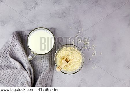 Rice Milk In A Mug, Rice Grains In A Glass Bowl On A Gray Background. Vegetable Milk. Vegan Without 