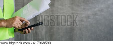 Construction Worker Hands Using Smartphone On Cement Wall Background With Copy Space