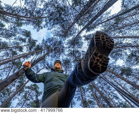 Tourist or sportsman with walking poles in the forest. Nordic walking.