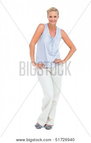 Woman standing with her hands on her hips smiling at camera on white background