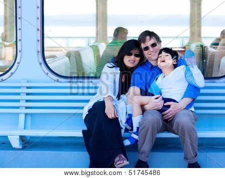 Interracial Couple Holding Disabled Son On Ferry Boat Deck