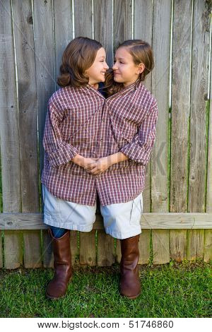 twin girls fancy dressed up pretending be siamese with his father shirt looking each other