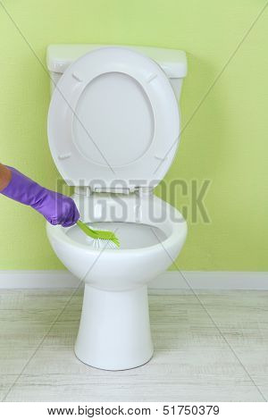 Woman hand with brush cleaning a toilet bowl in a bathroom